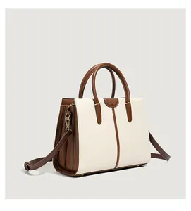 Detail view of contrast color handbag with sturdy dual handles and adjustable strap
