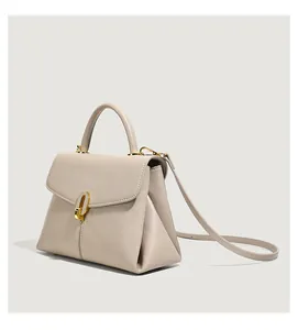 Detail view of beige lychee leather handbag with elegant gold oval twist lock closure
