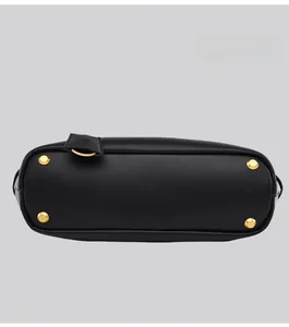 Detailed view of black leather tote bag bottom with four gold protective metal feet