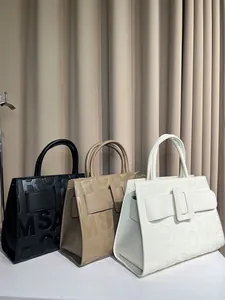 Detail of embossed letter pattern on three faux leather tote bags in various colors