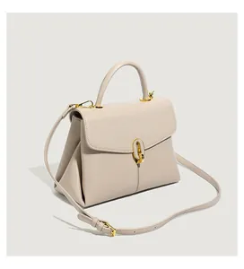 Detail of beige lychee texture leather handbag with gold hardware and shoulder strap