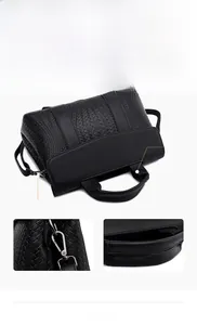 Detail of black woven texture handbag showing detachable strap and handles