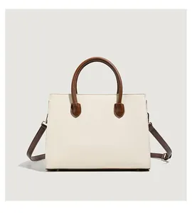 Detail view of the cream white handbag with brown leather handles and adjustable strap