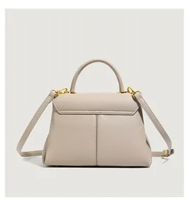 Detail of beige lychee leather handbag with gold hardware and protective base studs