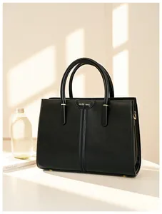 Close-up of black leather tote bag featuring gold Muse Bag logo and elegant metal hardware