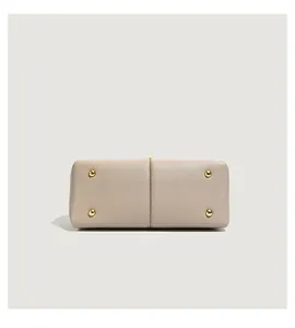 Close-up of beige lychee grain leather handbag base with four protective gold metal feet