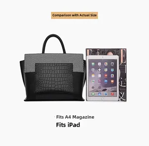 Detail view of large crocodile embossed tote bag next to A4 magazine and iPad for scale