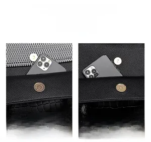 Detail of dual front pockets with magnetic clasps on black crocodile pattern tote bag