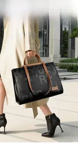 Detailed view of black embossed tote bag with brown handles and luxury textures