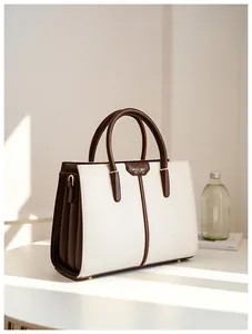 Detail of the MUSE BAG metal plate on the contrast color handbag with warm sunlight
