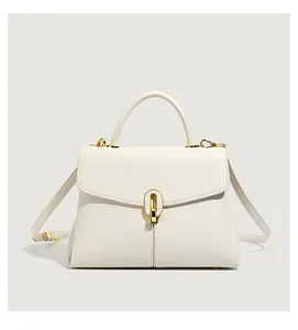 Detail of cream white leather handbag featuring litchi texture and golden oval swivel lock