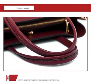Close-up of wine red litchi leather handbag handles and golden zipper detail