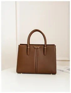 Detail of a brown leather tote bag with gold metal rings and MUSE BAG logo branding