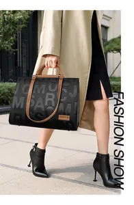 Fashionable black tote bag with embossed letters and brown handles in a street scene