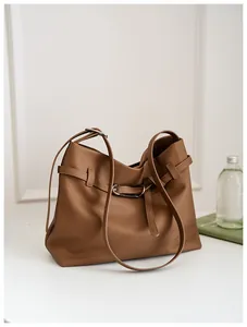 Detail view of brown pebbled leather tote bag with decorative buckle and adjustable strap