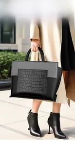 Detail shot of black tote bag featuring crocodile embossed leather and textured panels