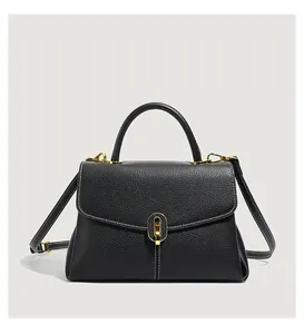 Detail of black pebbled leather handbag with gold oval lock and white stitching contrast