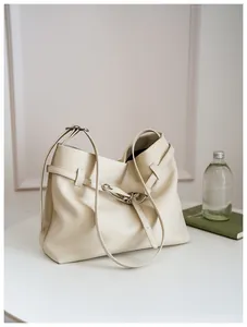 Detail of beige leather tote bag featuring a silver metal buckle and soft pleated texture