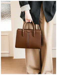Close-up of MUSE BAG brown leather handbag showing metal feet and textured finish
