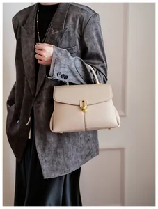 Detail of beige textured leather handbag with gold metal clasp and vertical stitching