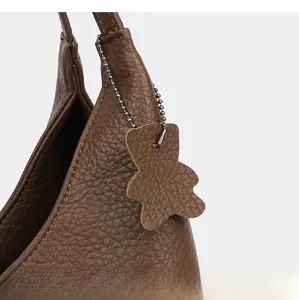 Close-up of brown lychee grain leather tote bag with a matching bear bag charm