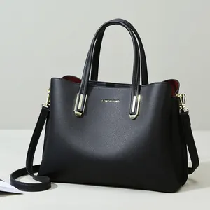 Close-up of black lychee grain leather handbag featuring gold hardware and red lining