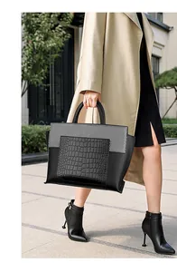 Detail of black faux crocodile leather tote featuring mixed textures and top handle