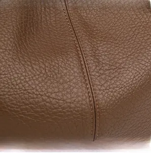 Macro detail of high-quality brown lychee leather and neat double-stitching process