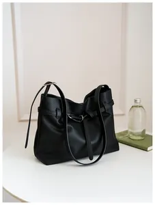 Detail of black lychee grain leather tote bag with silver metal buckle and strap