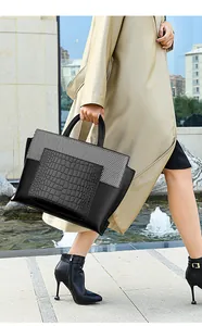 Detail showing the mixed texture of crocodile pattern and smooth leather on a tote bag