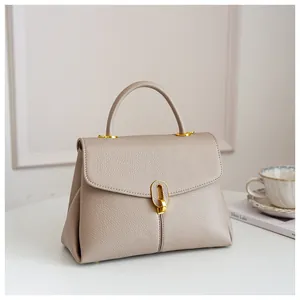 Macro shot of grainy leather texture and gold metal buckle on a beige women's handbag