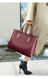Detail of burgundy leather tote bag featuring golden metal hardware and premium texture