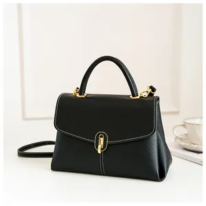 Detail of black pebbled leather handbag with gold twist lock and contrast white stitching