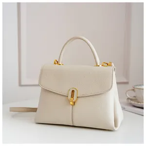 Detailed macro view of cream pebbled leather texture and golden metal lock on handbag