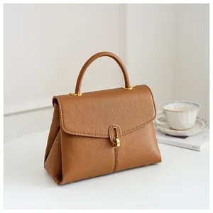 Detail view of brown textured leather handbag with elegant gold metal twist lock