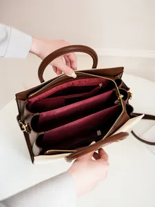 Contrast color handbag with spacious multi-compartment interior and gold hardware