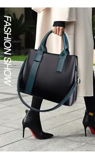 Detail van een grote trapezevormige leren tote tas met groene handvaten in modieuze setting
