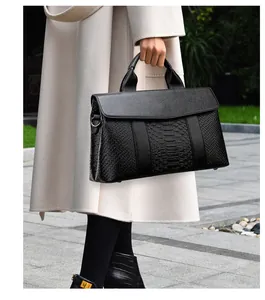 Detailed view of black tote bag featuring faux python skin texture and lychee pattern leather