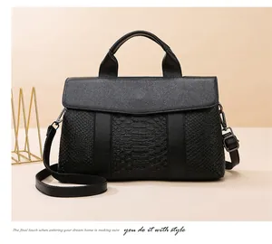 Detail view of black lychee leather handbag with snake pattern texture and dark hardware