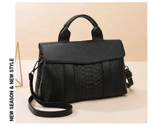 Detail of black faux crocodile leather tote bag featuring adjustable shoulder strap and handle