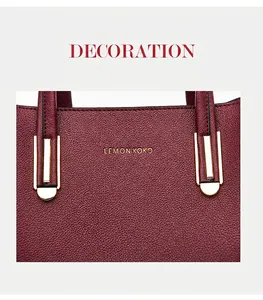 Detail showing burgundy pebble leather texture and gold metal hardware on the handbag
