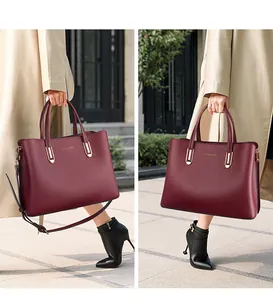 Macro detail of wine red pebbled leather tote bag with gold hardware and brand logo