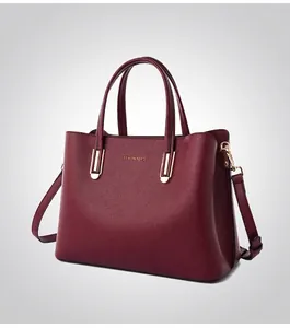 Macro side view of wine red pebbled leather handbag with elegant gold hardware