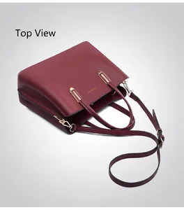 Close-up of burgundy lychee-grain leather texture with gold zipper and metal buckles