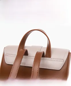 Detailed close-up of leather stitching and handle of the two-tone minimalist backpack