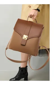 Detail of vintage brown leather backpack showing gold buckle and textured contrast stitching