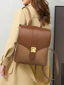Minimalist brown contrast leather backpack with golden square buckle on a female model