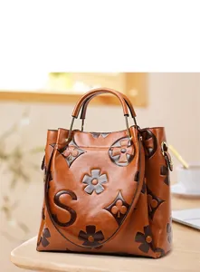 Detail of vintage brown leather bucket bag with embossed monogram and gold hardware