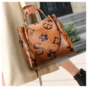 Detailed side view of brown embossed leather bucket bag with top handle and gold hardware
