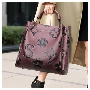 Detail shot of burgundy embossed leather texture with large S logo on the tote bag